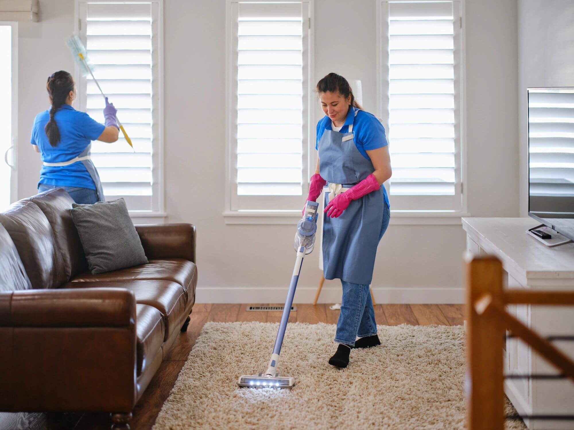 Woman mopping carpet in a bright living room.