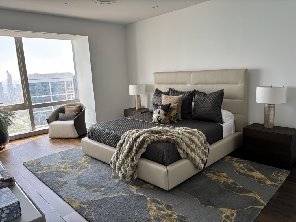 Neatly made bed in a clean, modern high-rise bedroom.