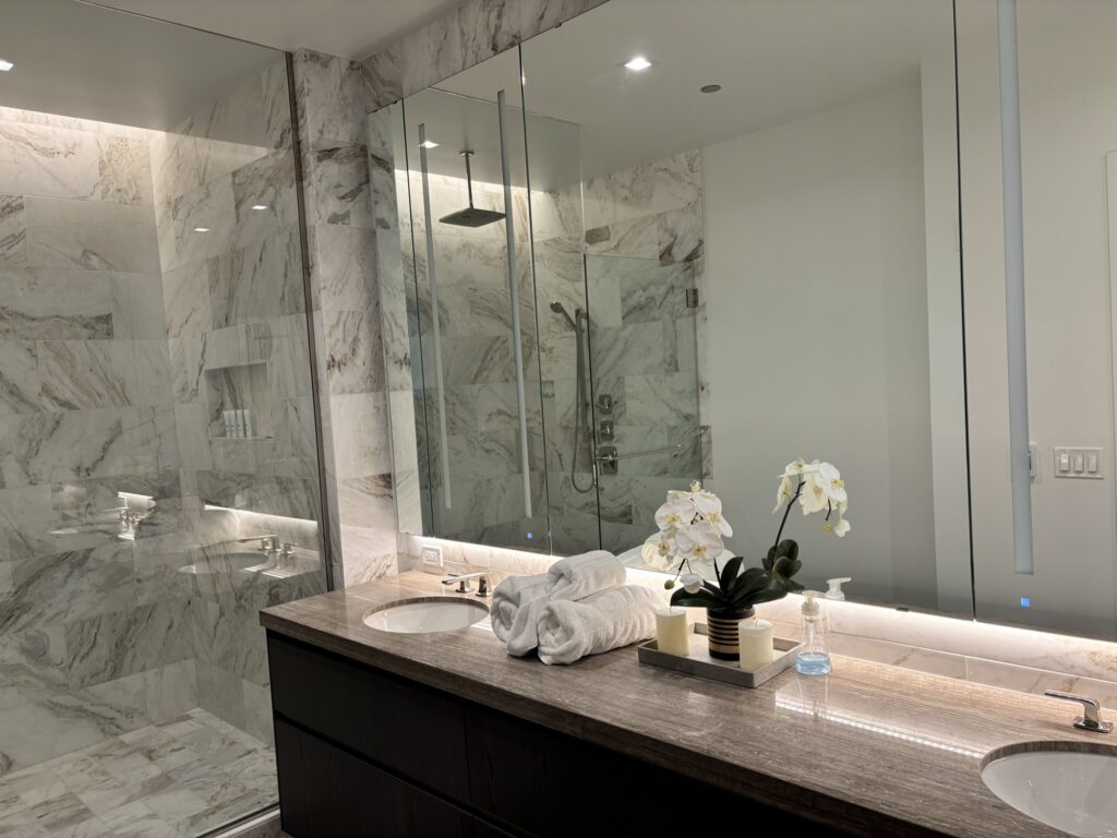 Sparkling marble bathroom with double vanity and glass shower.