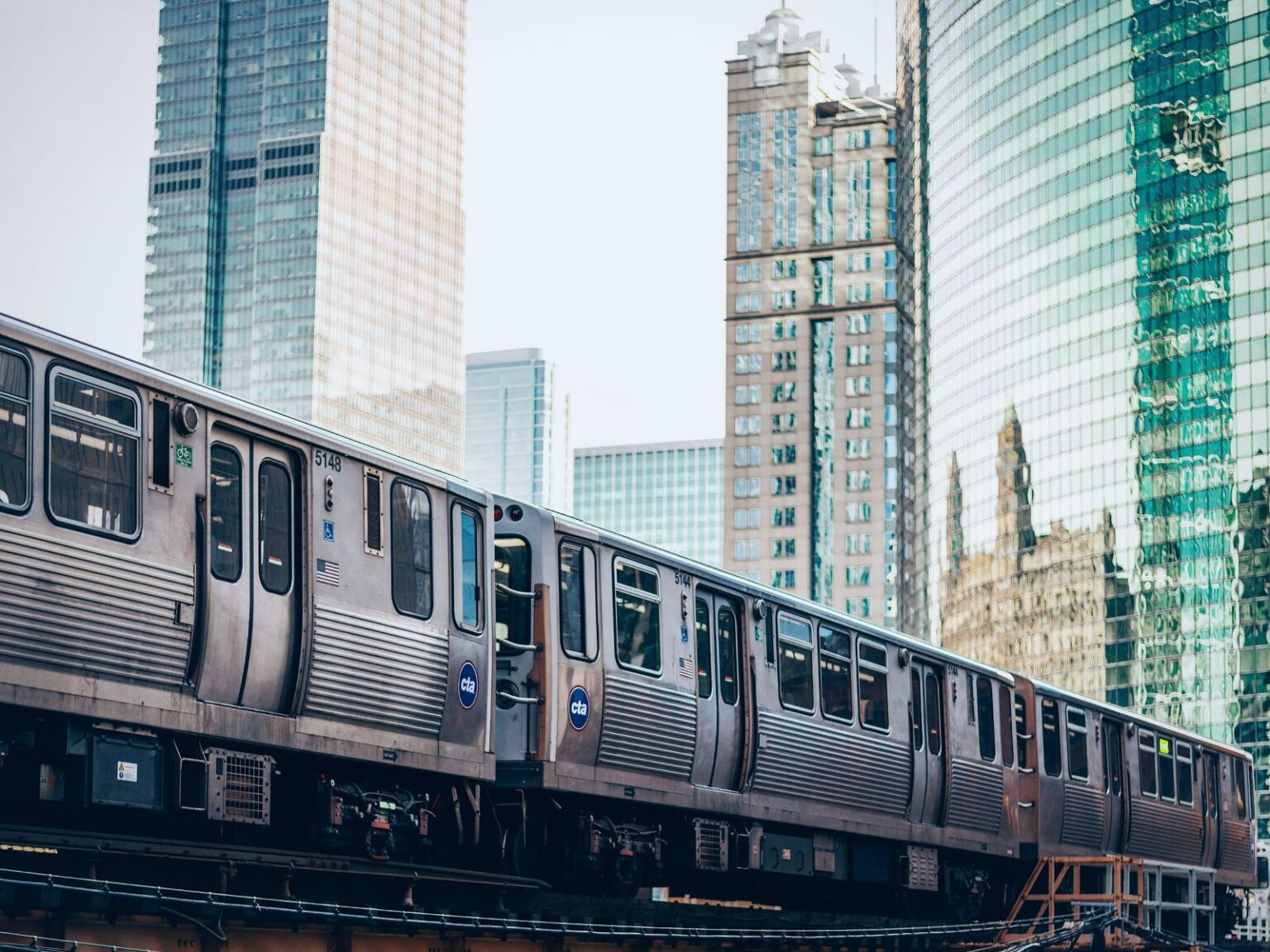 CTA "L" train crossing the elevated Loop tracks between downtown Chicago skyscrapers.